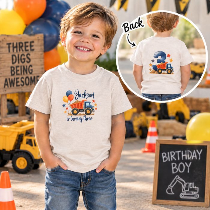 Toddler boy in a personalized dump truck birthday shirt with name and a big number 3 on the back