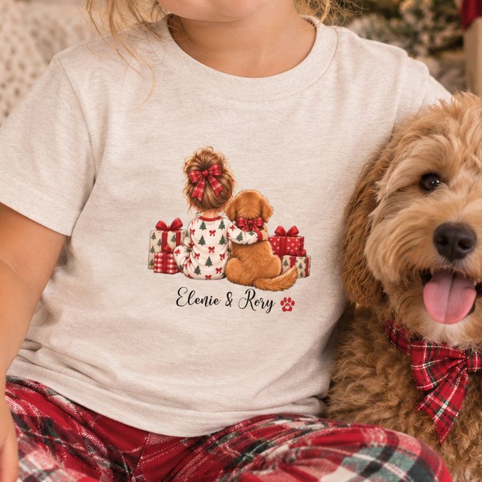 Toddler shirt showing a girl and her dog with presents and their names, worn beside a real dog